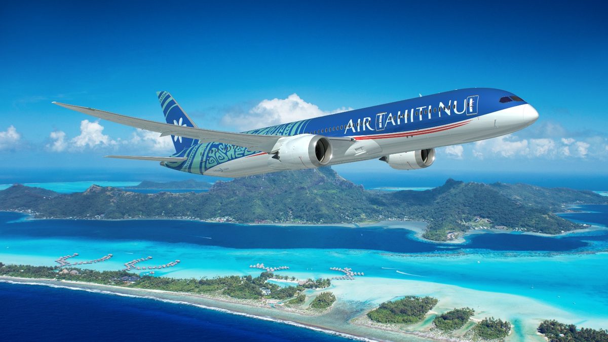 Un aereo Air Tahiti Nui in volo sopra Bora Bora, con la laguna turchese e i bungalow sull’acqua.